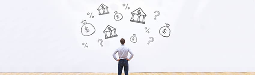 A man stands with hands on hips, looking at a whiteboard with doodles of banks, money bags, percentages, and question marks.